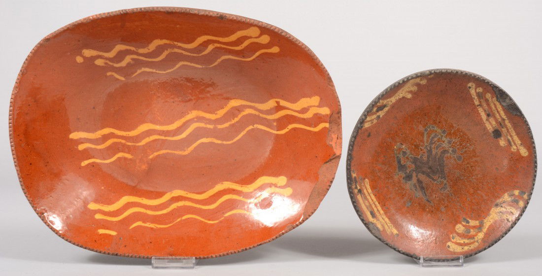 Two Redware Dishes. A large oval serving dish with: Two Redware Dishes. A large oval serving dish with rippled yellow slip lines and coggle rim, 15"l. X 11 1/2"w. Along with a round dish with yellow slip designs and a coggle rim, 9"dia. Condition: Larg