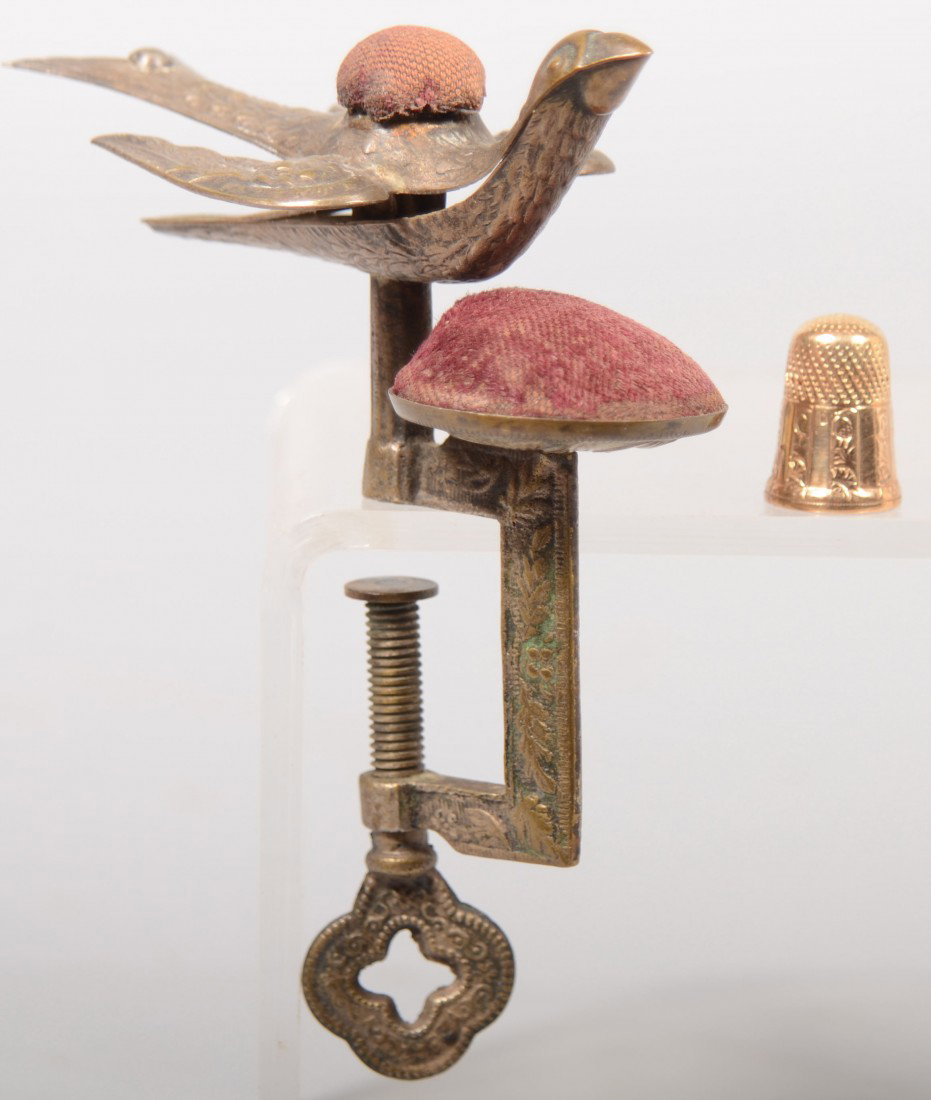Two Sewing Tools. A plated brass bird clamp with v: Two Sewing Tools. A plated brass bird clamp with velvet pin cushions, 5 1/4"h., along with a 10k. #6 gold thimble. Paneled lower half with engraved floral designs, 7/8"h. Condition: Clamp good with us