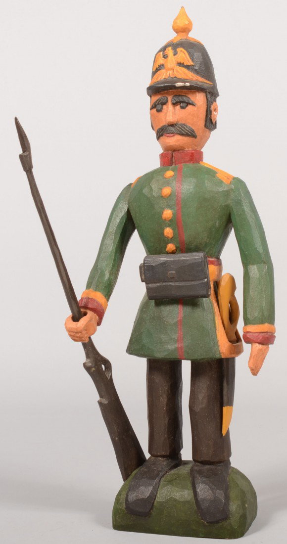 Jonathan Bastian Carved and Painted Wooden German : Jonathan Bastian Carved and Painted Wooden German Soldier. Green and red uniform of First World War style with spike helmet, side sword and bayoneted rifle. Standing on a wood block with carved identi