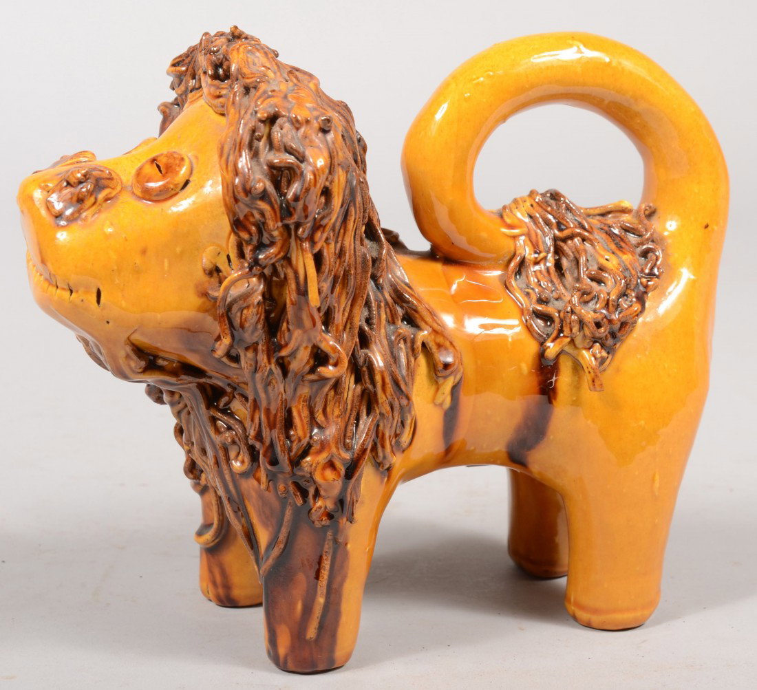 L. Breininger Free Standing Yellow Slip Lion. A th: L. Breininger Free Standing Yellow Slip Lion. A thick looped tail with 'spaghetti' tail tip and mane in manganese slip. Written underneath in slip: "L. B., '84, PA." 7 3/4"h. X 9"l. Condition: Good, n