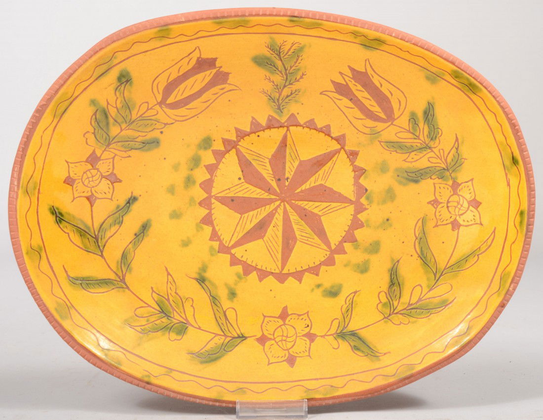 L.&B. Breininger Oval Redware Dish. Scraffito comp: L.&B. Breininger Oval Redware Dish. Scraffito compass star in center surrounded by posies, tulips and a serpentine border in the yellow slip ground nd with green accents. Coggle rim with inscription o