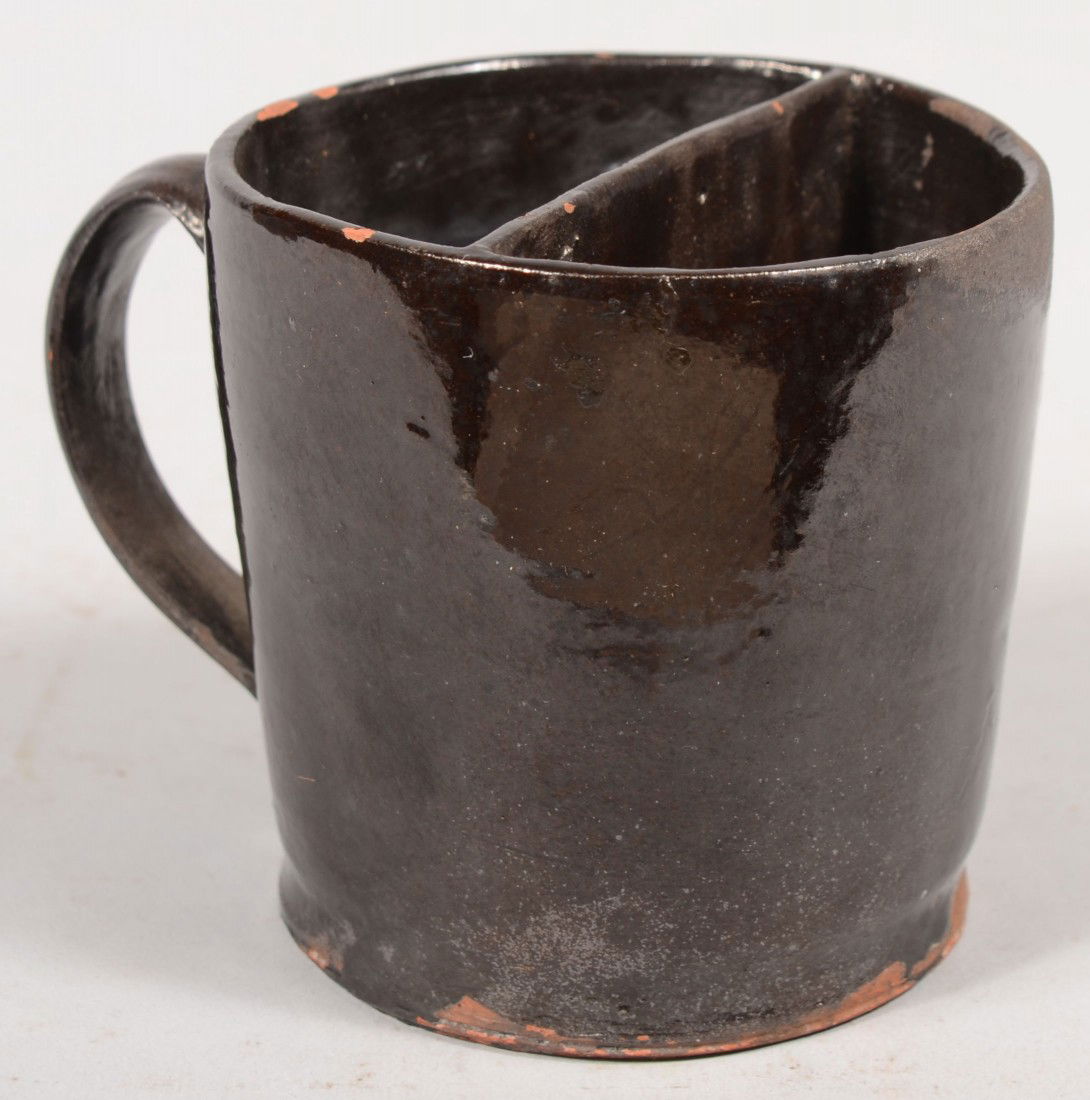 Redware Shaving Mug. Manganese glazed vessel with: Redware Shaving Mug. Manganese glazed vessel with divided soap compartment in upper half and applied loop handle. 4"h. X 4"dia. Condition: Eight small flakes off rim, one off handle and a small kiln b