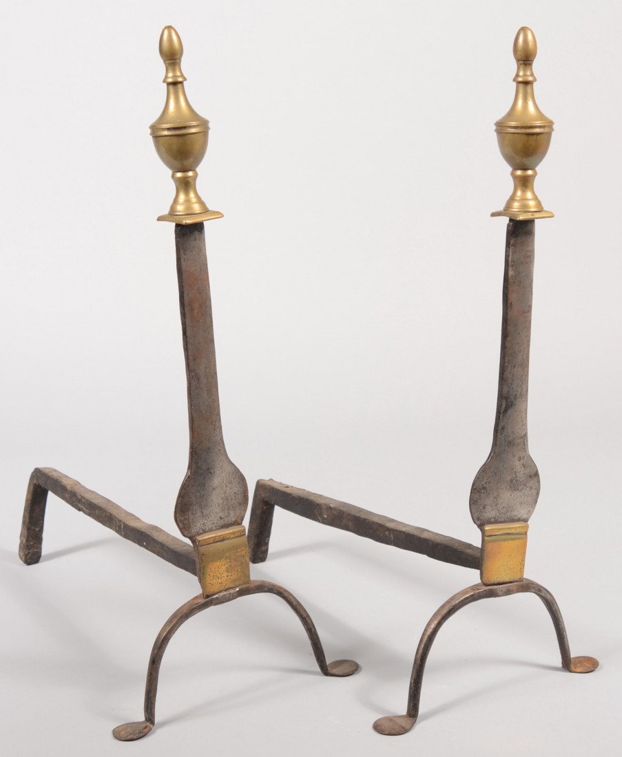 Pair of Wrought Iron and Brass Andirons. Stirrup s: Pair of Wrought Iron and Brass Andirons. Stirrup style legs with 'penny' feet supporting a baluster shaped knife blade guards in iron. Top of blade surmounted by a brass plate and urn shaped finials. 