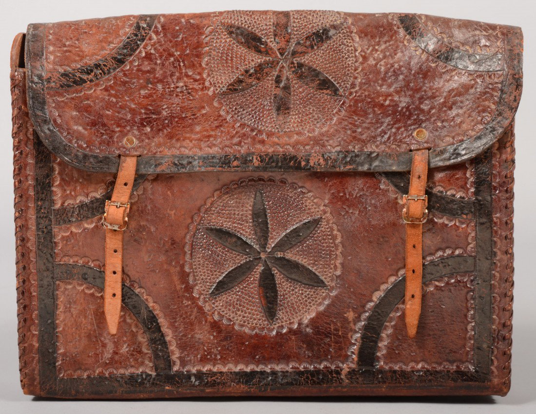 Tooled Leather Back Pack. Pinwheel design on box a: Tooled Leather Back Pack. Pinwheel design on box and cover with quarter round corner decorations. Seams lashed together with leather lacing. Cover and shoulder straps with small metal buckles. Unmarke