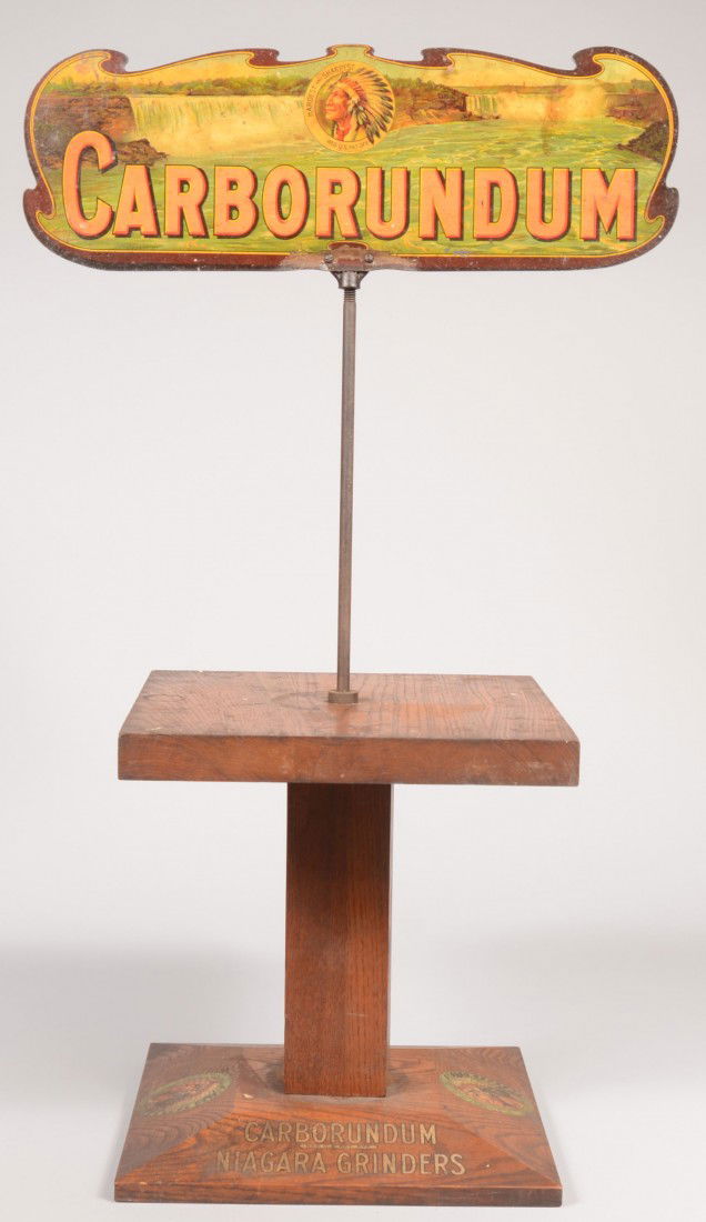 Carborundum Brand Oak Pedestal Display with Metal: Carborundum Brand Oak Pedestal Display with Metal Sign. Beveled base with decals of Indian chief and Brand names. Square post supporting a square oak plank table with a steel rod mounted in the center