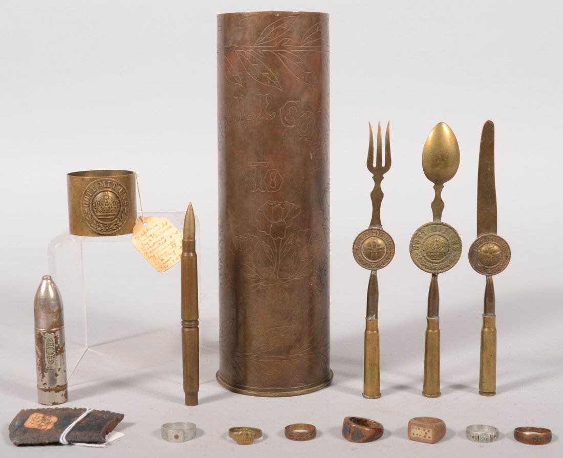 Lot of WW1 trench art including a knife, fork, spo: Lot of WW1 trench art including a knife, fork, spoon, and napkin holder set, a 75mm shell "Welcome to Americans Verdun 1918", a pointer tip, a cigarette lighter, and 7 finger rings.