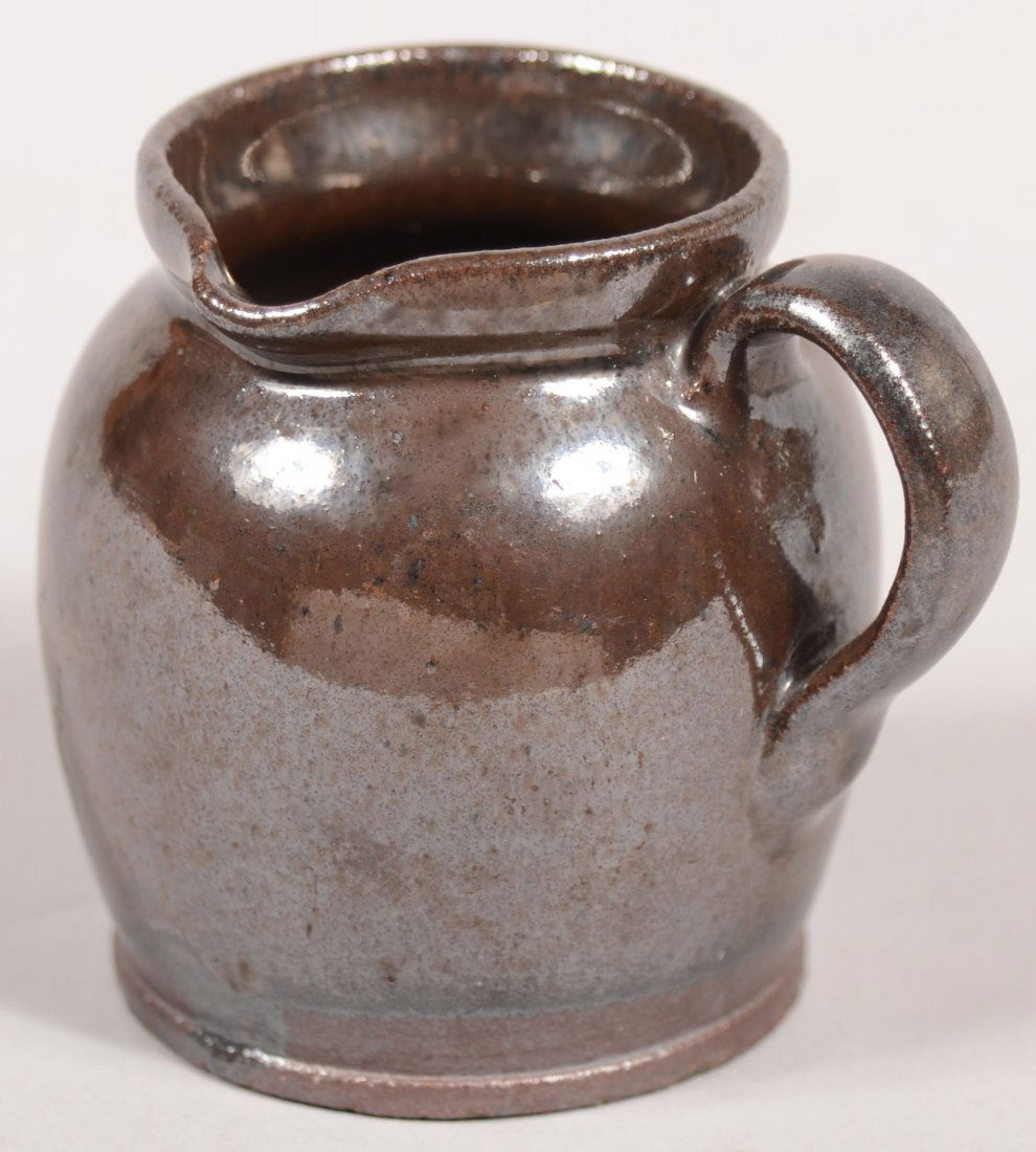 Miniature Pennsylvania 19th Century Redware Potter: Miniature Pennsylvania 19th Century Redware Pottery Bulbous Form Side-spout Pitcher with applied loop handle and manganese glaze. 2 1/8"h.