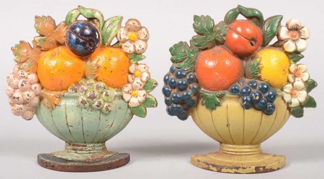 Two Painted Cast Iron Door Stops. Footed bowl with: Two Painted Cast Iron Door Stops. Footed bowl with fruit and flowers relief cast iron doorstop. Only mark a production number. Possibly Hubley. 7"h. X 6 1/2"w.