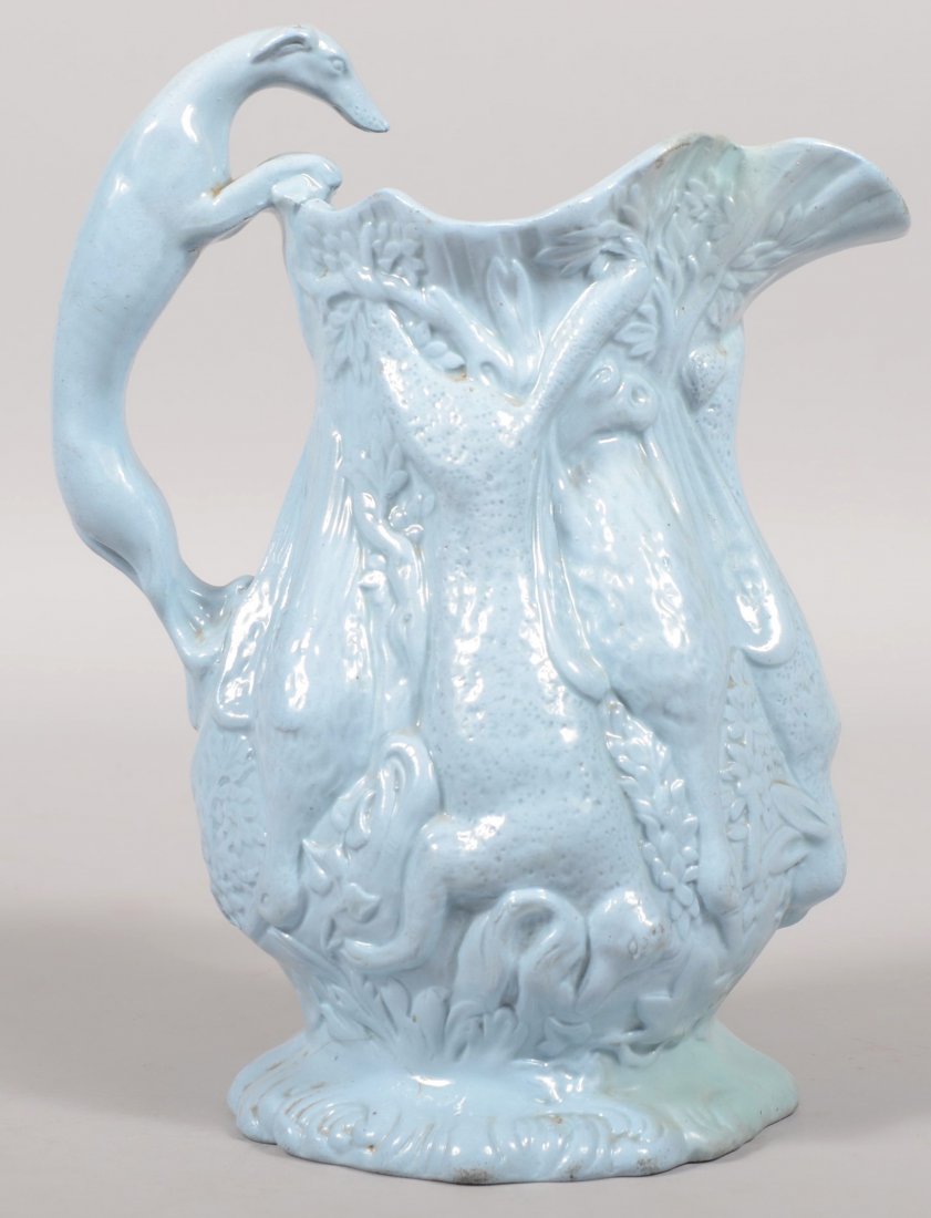 A Blue Cast Glazed Parian Pitcher. Hanging woodlan: A Blue Cast Glazed Parian Pitcher. Hanging woodland game relief decoration make up the body of this pitcher with an applied whippet handle. 11"h.