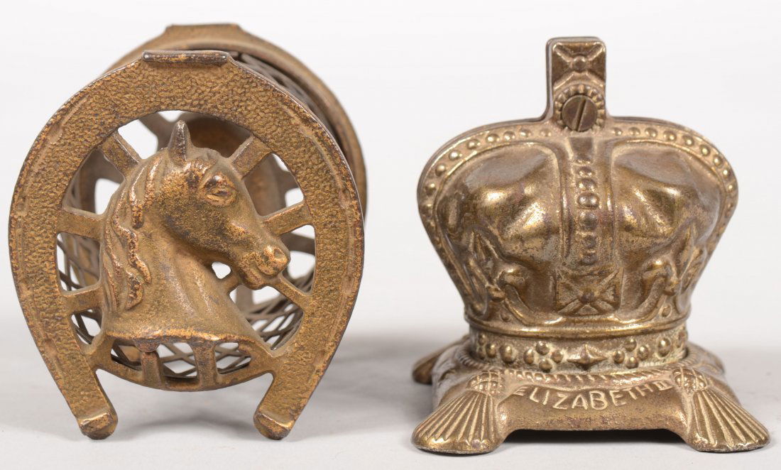 Two Cast Iron Penny Still Banks. Two horseshoes wit: Two Cast Iron Penny Still Banks. Two horseshoes with horse heads separated by a die punched expanded metal cylinder in gold and black paint. Mfg. by Arcade. 3 1/4"h. X 3"l. Together with a Queen Eliza