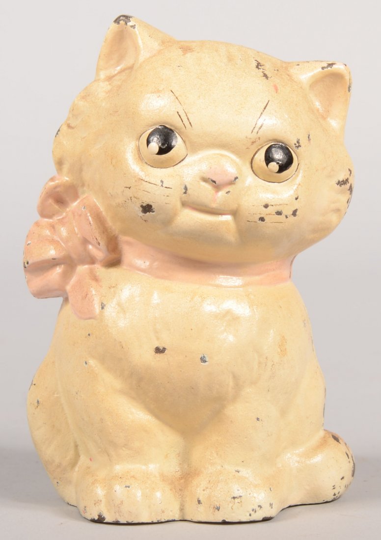 Hubley Kitty Still Bank. White painted cast iron ki: Hubley Kitty Still Bank. White painted cast iron kitten with black facial features and a pink neck ribbon. 4 3/4"h.