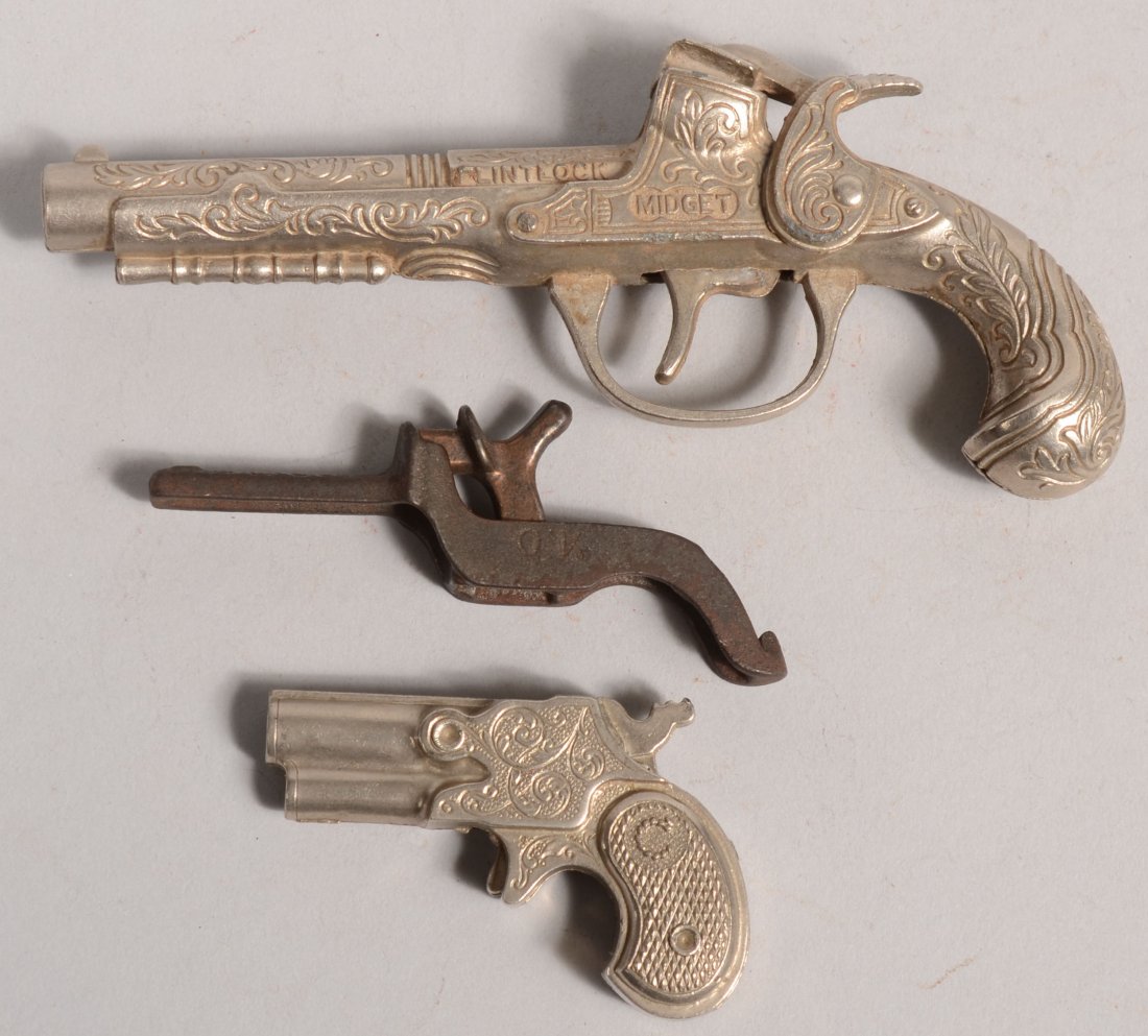 Three Cast Metal Cap Pistols. A Hubley "Flintlock : Three Cast Metal Cap Pistols. A Hubley "Flintlock Midget", 5 1/2"l.; Unmarked derringer, 2 3/8"l.; a small cast iron pistol marked: "OK, USA, Pat. June 17, '92", 3 1/4"l.