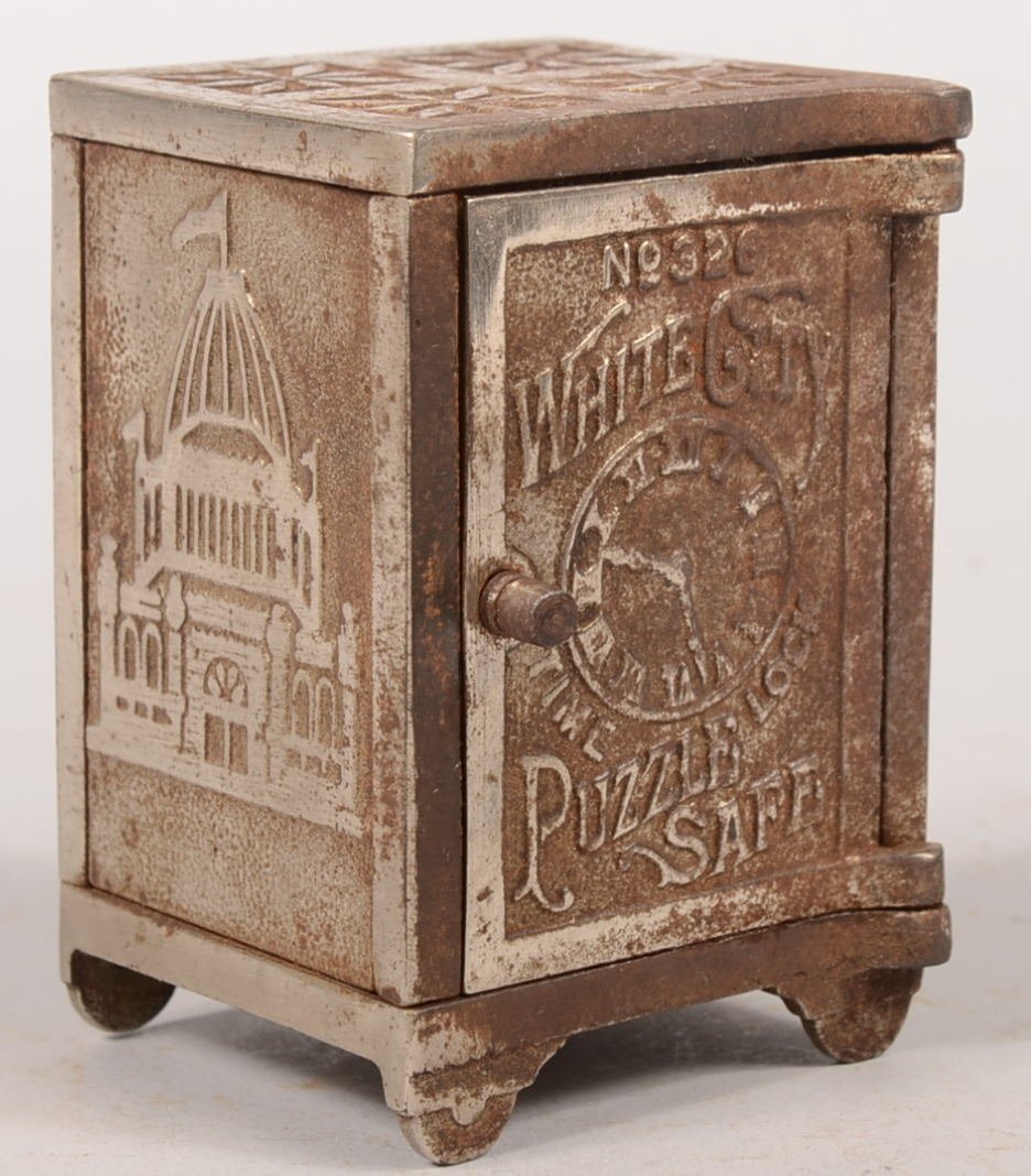 White City No. 326 Puzzle Safe with Time Lock Stil: White City No. 326 Puzzle Safe with Time Lock Still Bank. Nickel plated safe has panels with bas-relief illustrations of buildings from the 1893 Chicago World's Exhibition bank and produce in same yea