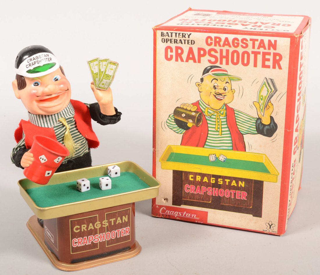 Animated Figural Toy "Cragstan Crapshooter." Batte: Animated Figural Toy "Cragstan Crapshooter." Battery operated motor powers natural rubber face chewing motion and shakes cup and rolls dice onto table while waving the cash. Toy with original box. 9"h