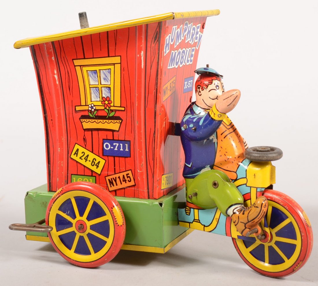 Humphrey Mobile Animated Wyandotte Wind-up Toy. Li: Humphrey Mobile Animated Wyandotte Wind-up Toy. Lithographed tin toy tricycle with "Out house" home on back of chassis. Hat pops up and down and he waves his arm when moving. 7 1/4"h. X 9"l.