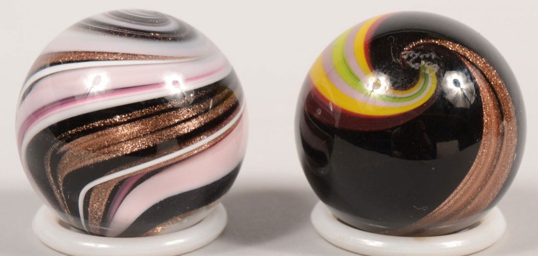 Two Contemporary Marbles Signed by "John H. Miller: Two Contemporary Marbles Signed by "John H. Miller." A multi-band swirl of pink, black, white and copper dust strands. Signed on end: "JHM, 97." 1 5/16"dia. Along with another black marble with a copp