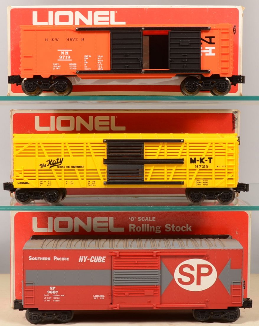 Three Lionel Rail Cars. 9725, MKT Cattle Car in ye: Three Lionel Rail Cars. 9725, MKT Cattle Car in yellow with black gates and lettering; 9719, orange New Haven Double Door Box Car with black doors; 9607, Southern Pacific Hi-Cube Box Car in red with g