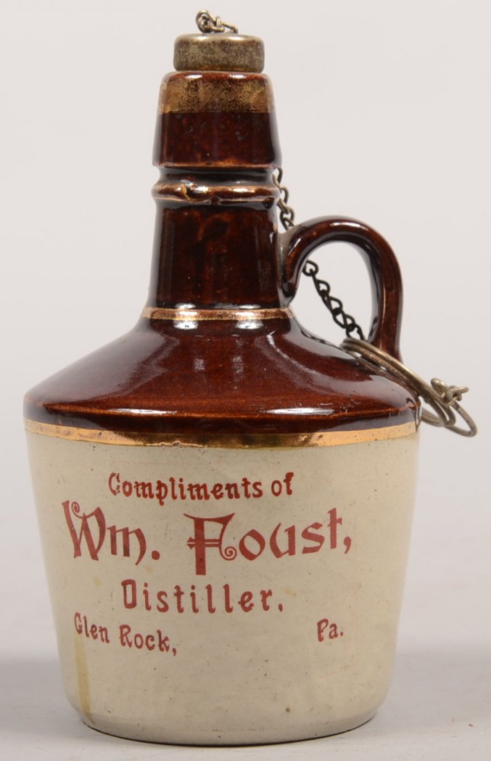 Small Stoneware Whiskey Jug from Glen Rock, PA. Mo: Small Stoneware Whiskey Jug from Glen Rock, PA. Molded stoneware jug has manganese dipped top half with bottle neck and applied loop handle. Spout and neck have gilt rings and silver plated cork with 