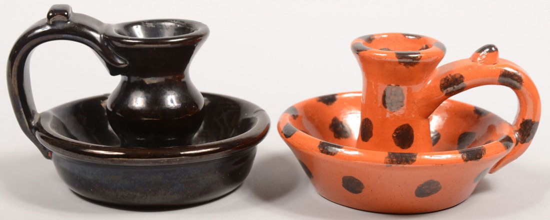 Two Seagraves Marked Redware Chamber Candlesticks.: Two Seagraves Marked Redware Chamber Candlesticks. Both with stemmed sockets in circular dishes with an applied loop handle. One has manganese spots and initialed on bottom. 3"h. X 4 3/4"dia. Other in