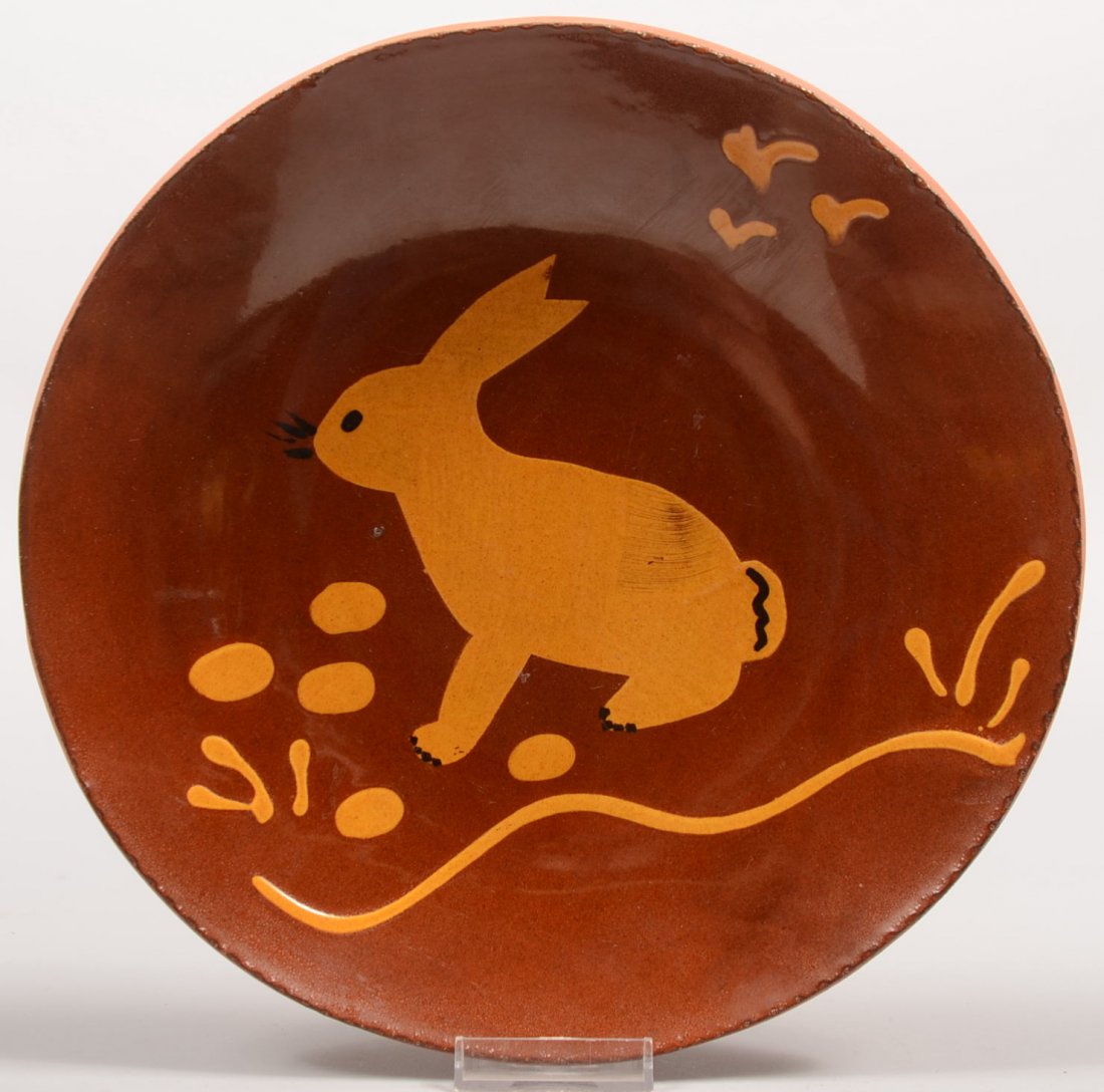 L. Breininger Marked Redware Dish. Center exhibits: L. Breininger Marked Redware Dish. Center exhibits a rabbit silhouette with eggs in yellow slip. Coggle rim and backmarked: " L. Breininger, Robesonia, PA. Feb. 15, 1989, Rainy day." 1 5/8"h. X 10 1/2