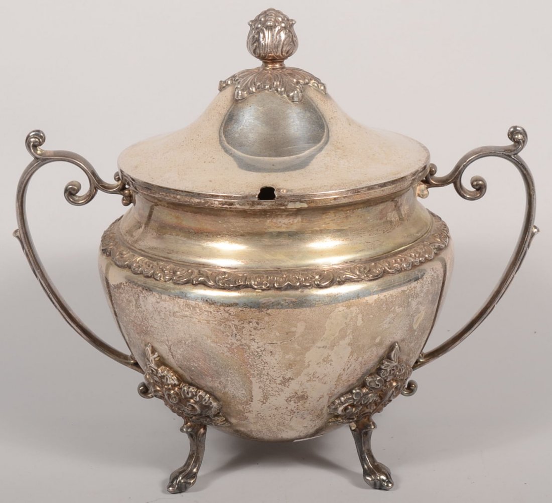 A Large Silver Plate Soup Tureen. A cup shaped bod: A Large Silver Plate Soup Tureen. A cup shaped body with reduced concave collar. Applied cast loop handles, legs, band at shoulder and finial on domed lid. Marks on bottom for Goldfeder Silverware Co.