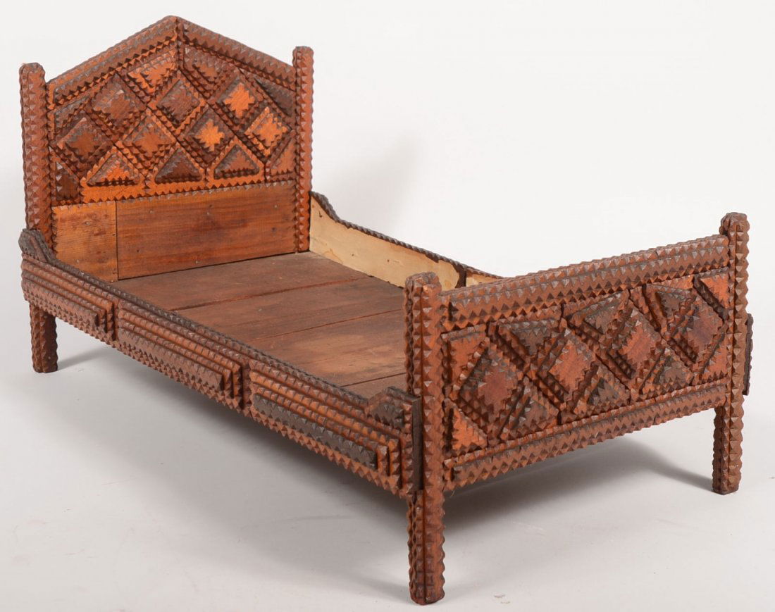Tramp Art Chip Carved Doll Bed. Peaked headboard a: Tramp Art Chip Carved Doll Bed. Peaked headboard and flat topped footboard have chip carved pyramids of squares and triangles on both sides that resemble a quilted texture. Legs, rails and posts all c