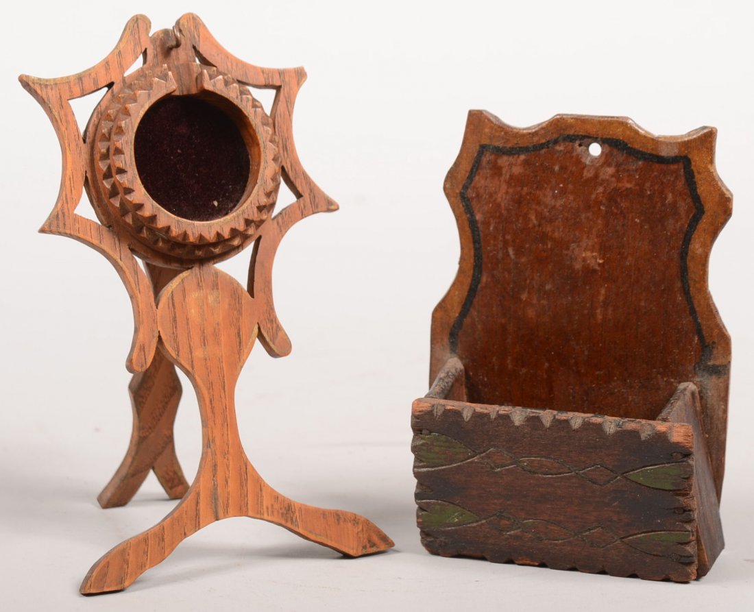 Two Small Tramp Art Carved Wood Objects. A easel t: Two Small Tramp Art Carved Wood Objects. A easel type watch stand. Chip carved bezel on a three leg scroll saw cut stand. Watch frame lined with maroon velvet. 6 3/4"h. Along with a small wall pocket 