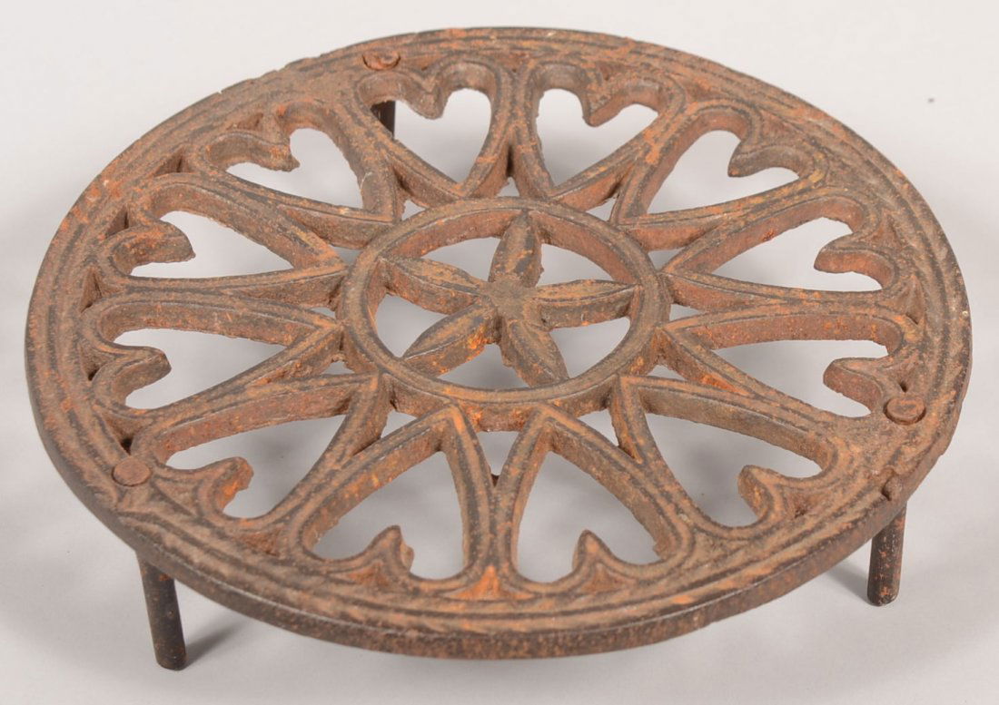 Cast Iron Trivet circular form with central five p: Cast Iron Trivet circular form with central five pointed star surrounded by hearts, three peg leg base. 2 1/8"h x 7 7/8" diam. Condition: Good with some surface rust.