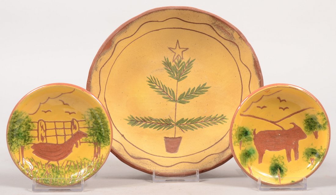 Three Redware Dishes with Yellow Slip Decoration. La: Three Redware Dishes with Yellow Slip Decoration. Largest by Pam Ambrust shows a small incised Christmas Tree with a star and over glaze green foliage. Signed on back. 7 5/8"dia. Along with two small