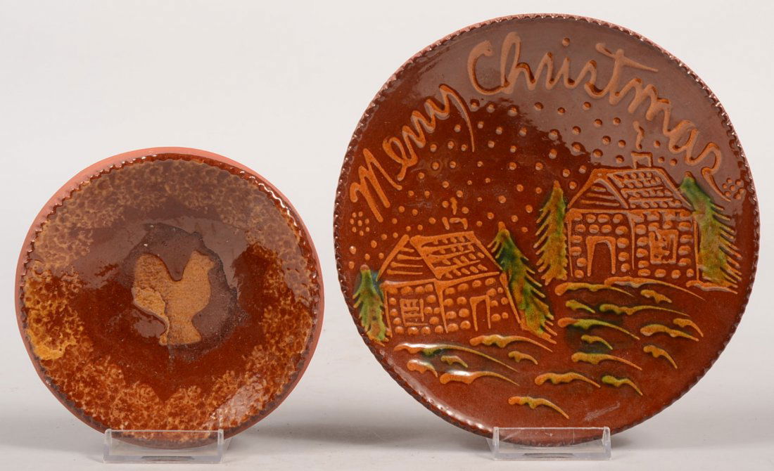 Two Ned Foltz Redware Dishes. A slip decorated "Merr: Two Ned Foltz Redware Dishes. A slip decorated "Merry Christmas" dish showing two log cabins and pine trees with coggle edge. Signed, stamped and dated: 1990. 7 1/4"dia. Along with another dish with s
