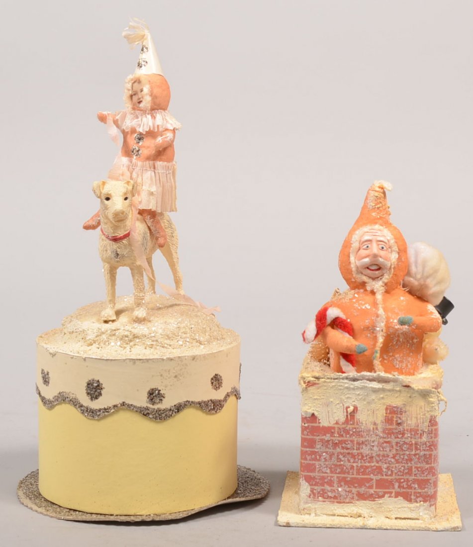 Two Handmade Christmas Whimsies. A cotton sculpture: Two Handmade Christmas Whimsies. A cotton sculpture of Santa emerging from a chimney top with sack, candy cane, snowman and small tree. Unmarked. 7"h. Along with a decorated cardboard cake shaped gift