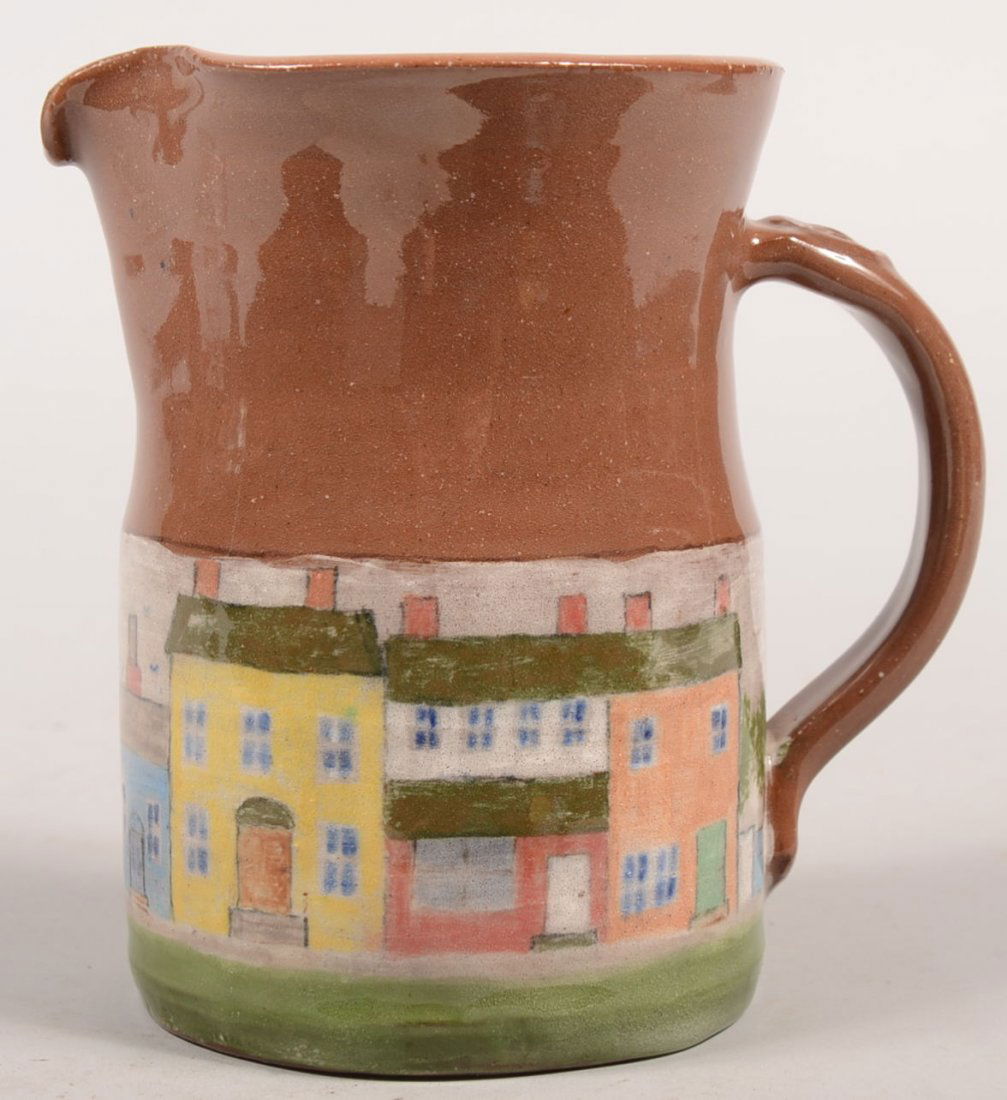 Left Handed Russell Henry Decorated Redware Pitcher: Left Handed Russell Henry Decorated Redware Pitcher. Vessel has a band of hand painted scenery at it's base including five row houses, shrubbery and a fence in multiple colors on white. Applied loop h