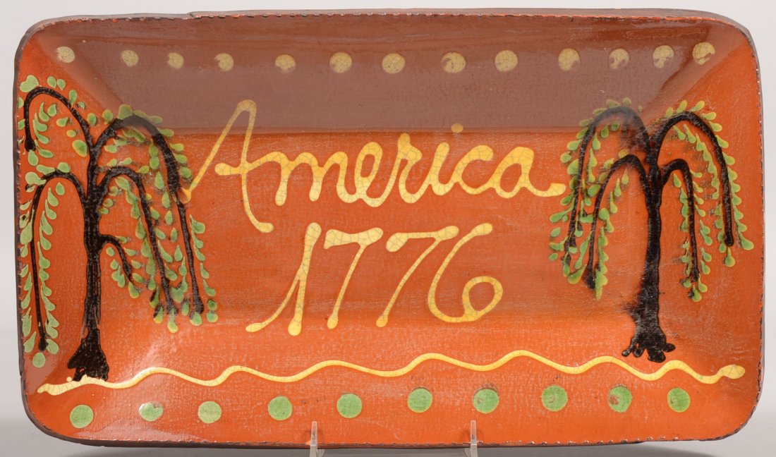 Rectangular Redware Loaf Dish by Turtle Creek. Cogg: Rectangular Redware Loaf Dish by Turtle Creek. Coggle rim surrounds two green and black slip willow trees flanking "America, 1776" with green and yellow slip dots across top and bottom borders. Signed