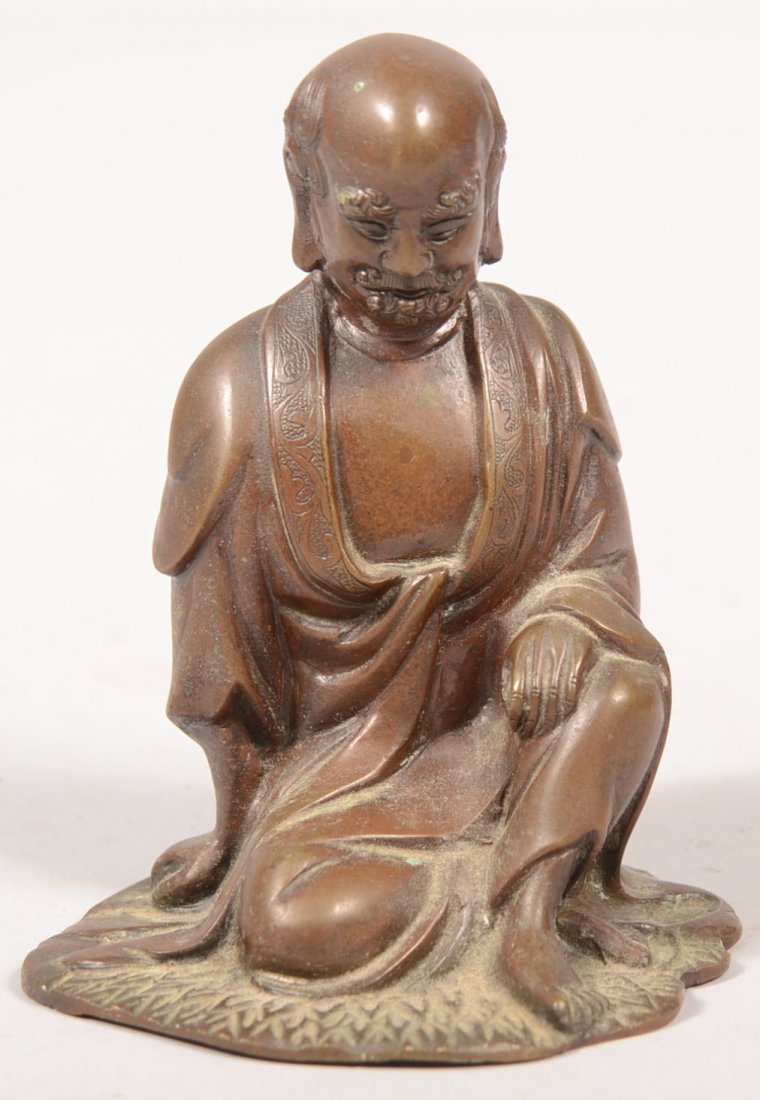 Hollow Cast Bronze Figure of a man kneeling upon a: Hollow Cast Bronze Figure of a man kneeling upon a lotus leaf. Moustache and goatee facial hair and a bald pate. Wearing an open robe. Unmarked. 4 1/4"h. X 3 1/2"across base.