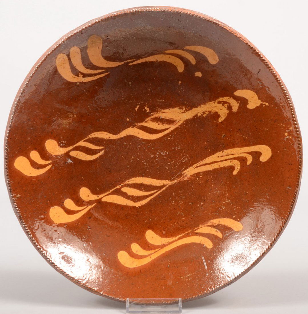 Slip Decorated Redware Dish. Four twisted groups o: Slip Decorated Redware Dish. Four twisted groups of three lines each decorate this coggle rim dish. Unmarked. 10 3/4"dia.