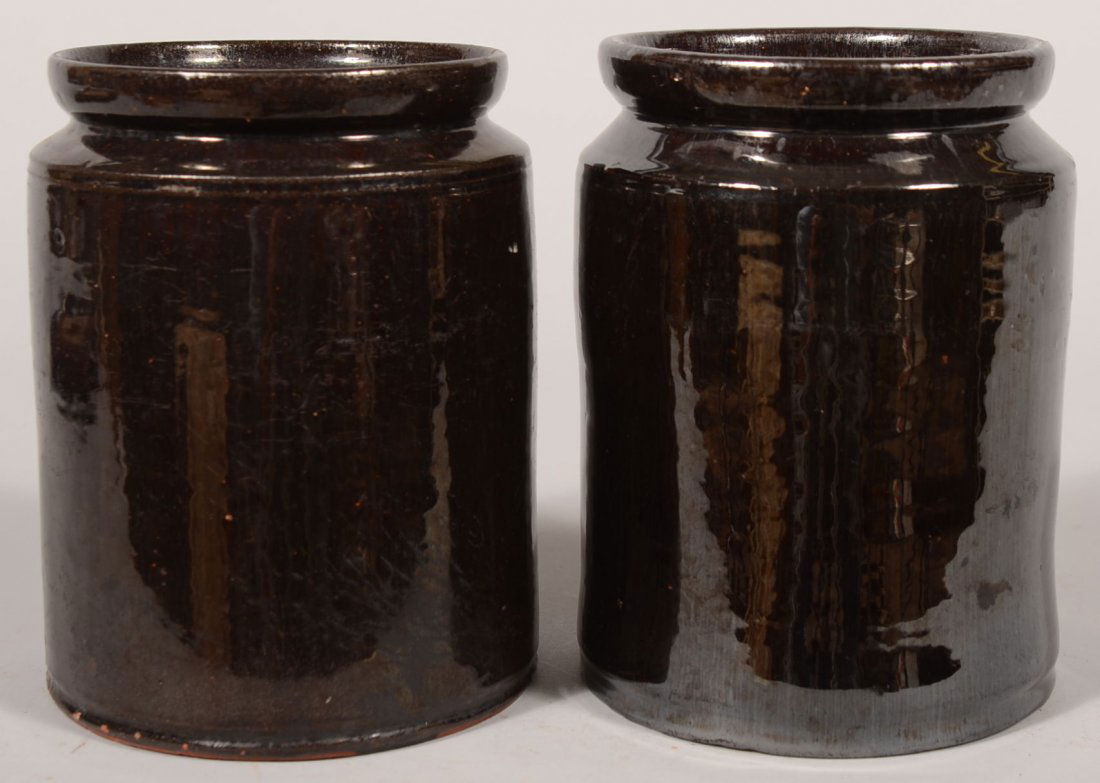 Two Redware Jars. Two nearly identical manganese g: Two Redware Jars. Two nearly identical manganese glazed straight sided jars with short beveled shoulder and cupped mouth. Mouth has an interior shoulder for a lid. No lids. 7 7/8"h.
