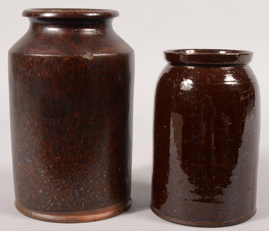 Two Straight Sided Redware Jars. Taller has a foot: Two Straight Sided Redware Jars. Taller has a foot bead, dark matte manganese glaze, short taper to rolled concave rim, 10 1/4"h. X 6"dia. Along with another having a base bead, rounded shoulder to a