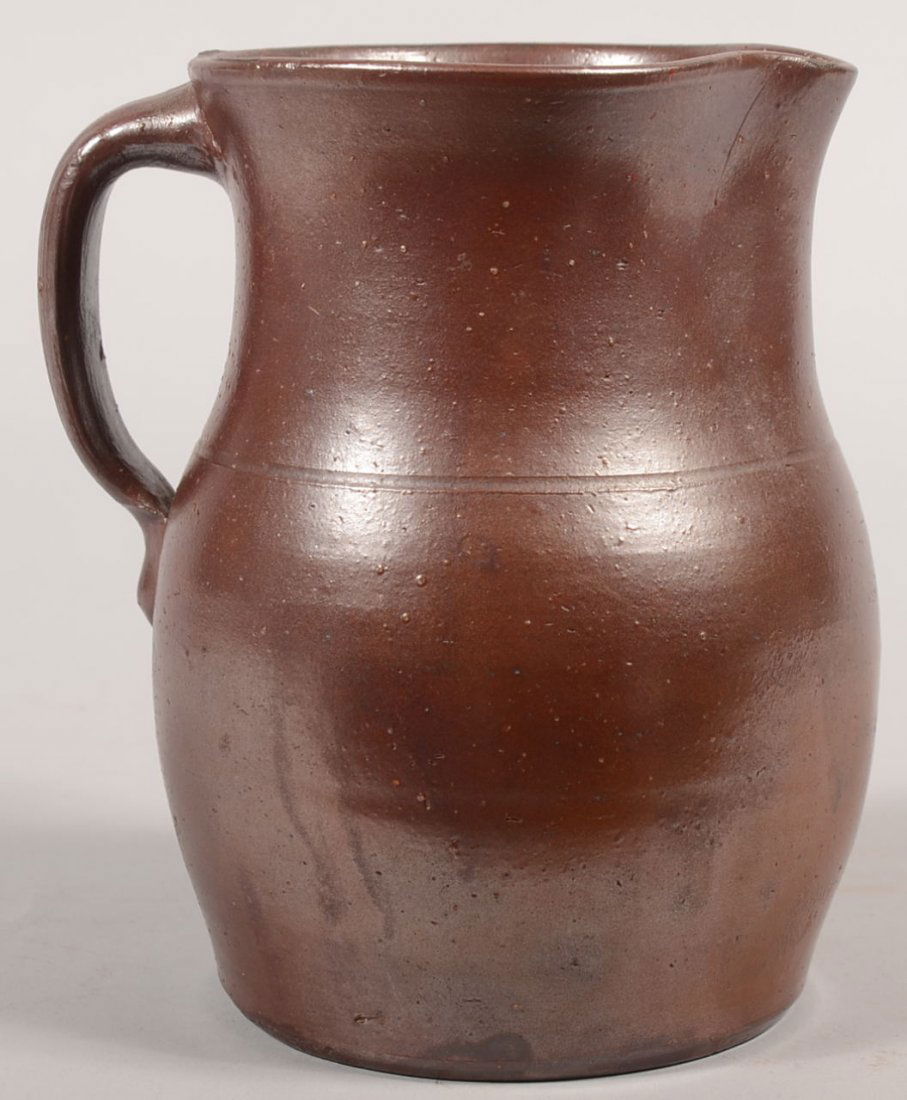 Redware Pitcher with Manganese Glaze. Bulbous body: Redware Pitcher with Manganese Glaze. Bulbous body with concave neck to flared rim and pulled spout. Applied D shaped handle. 7 1/2"h. X 5 1/4"dia.