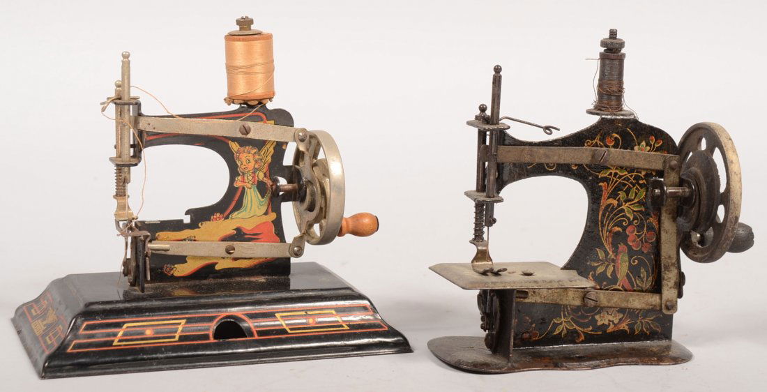 Two Small Painted Sheet Metal Sewing Machines. One: Two Small Painted Sheet Metal Sewing Machines. One marked: "Casige, 121" with color decals of a boy playing Wm. Tell and a pixie angel with line decorated base and a nickel plated flywheel with knob.
