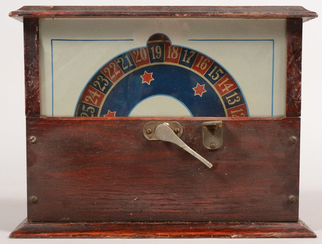 Oak Counter Top Coin Operated Gambling Device. Lev: Oak Counter Top Coin Operated Gambling Device. Lever activated wheel in blue and red behind glass panel. Coin slot on top right. Locked coin removal door on backside. Electrical wiring for interior li