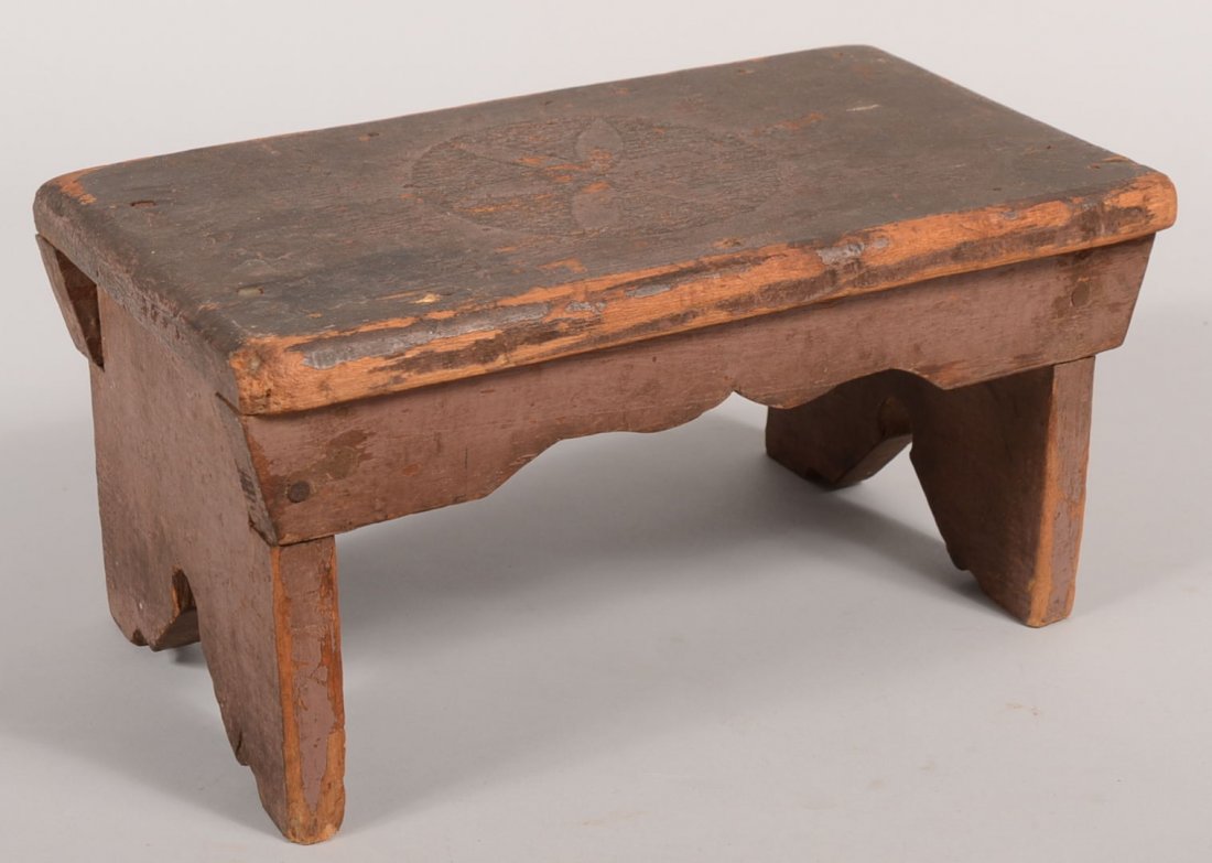Salmon Painted Plank Foot Stool. Keyhole style cut: Salmon Painted Plank Foot Stool. Keyhole style cut-out between feet, shaped skirt and a incised compass star design on center top of seat. 6 3/4"h. X 14"l. X 8"w.