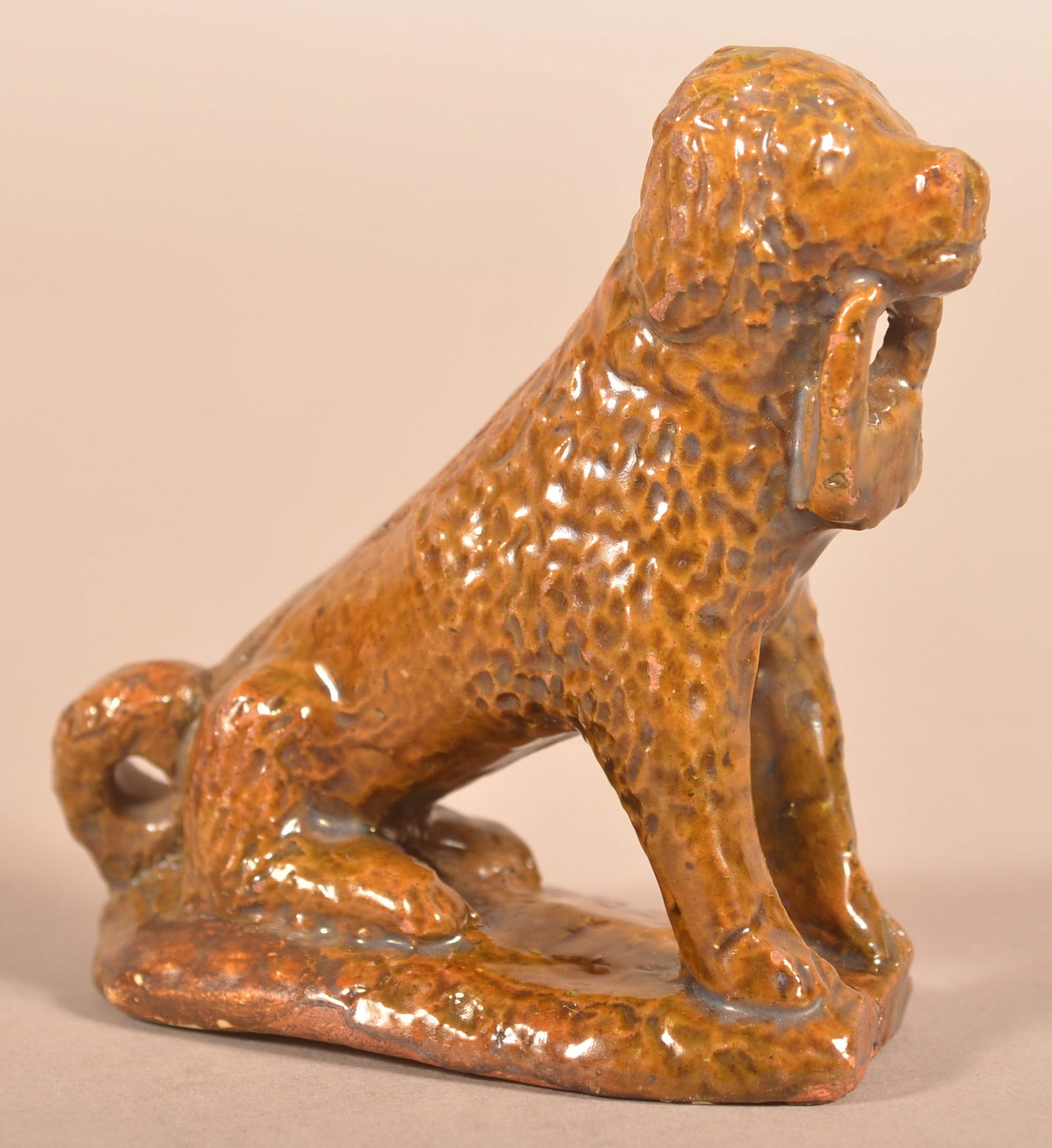 Pennsylvania 19th Century Redware Seated Spaniel.: Pennsylvania 19th Century Redware Seated Spaniel Figure. Hand-molded glazed figure of a dog with incised fur and holding a basket in mouth. 4-1/4"h.