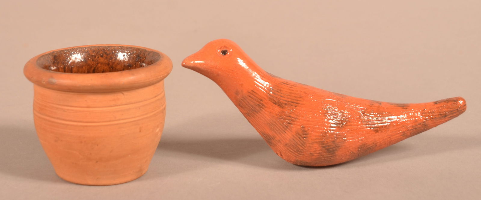 Two Pieces of Redware Pottery.: Two Pieces of Redware Pottery. Thomas Stahl 1942 miniature crock, 2-3/8"h. and a James Seagreaves glazed and molded pottery bird figurine, 6"l.
