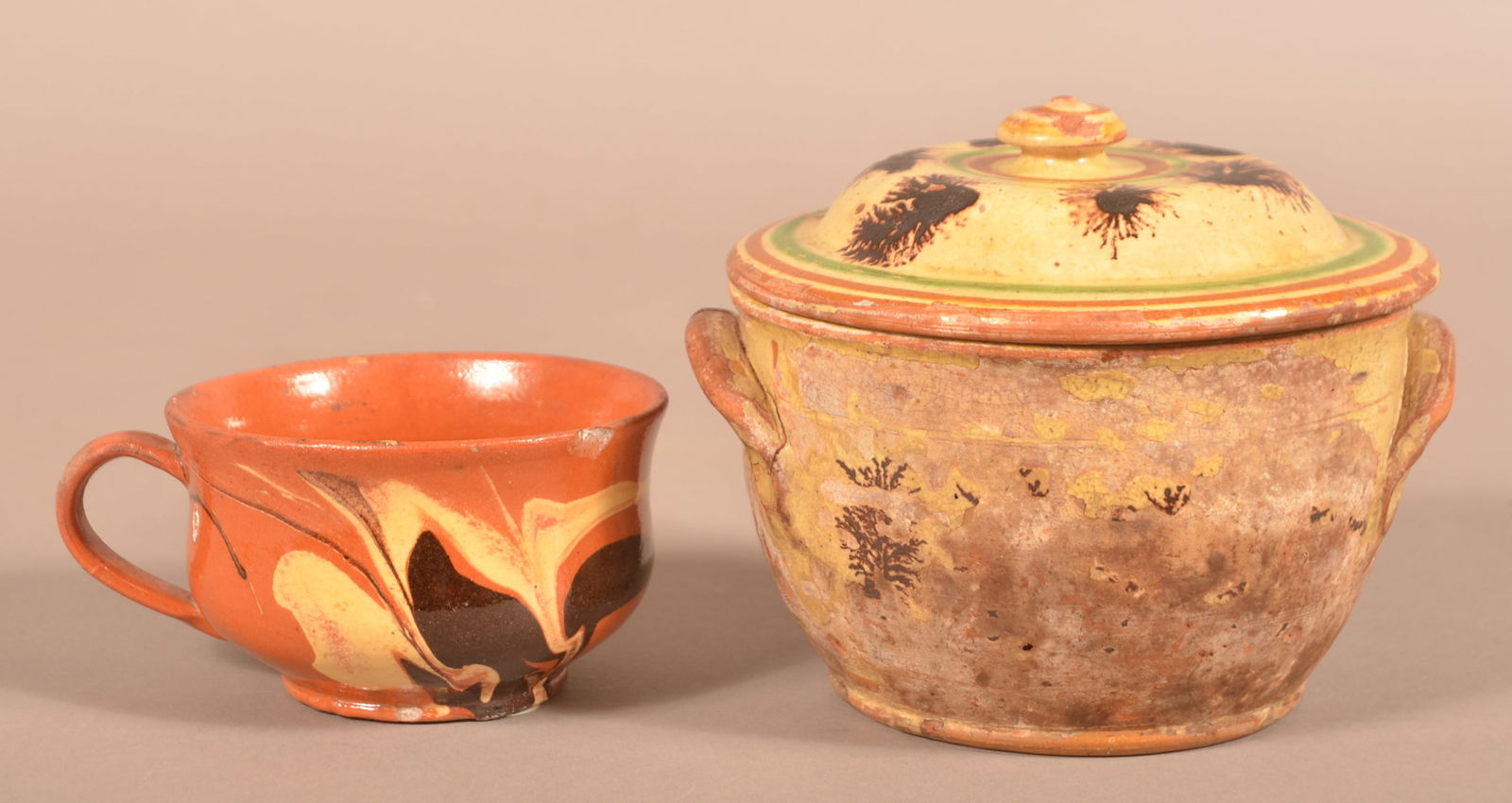 Two 19th Century Slip-Decorated Redware Vessels.: Two 19th Century Slip-Decorated Redware Vessels. Covered sugar bowl with seaweed mocha decoration, 5"h. and a flared rim mug, 2-1/2"h.