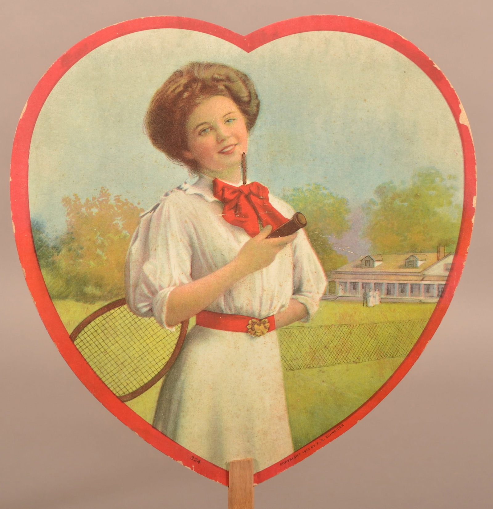 Iron City Beer Heart-Shaped Advertising Cardboard Fan.: Iron City Brewing Co., Lebanon, PA. Lithograph depicts a young lady holding a tennis racket, copyright 1910 by F.A. Schneider. Manufactured by The Quality Print Shop, Lebanon, PA. 8" x 13" overall.