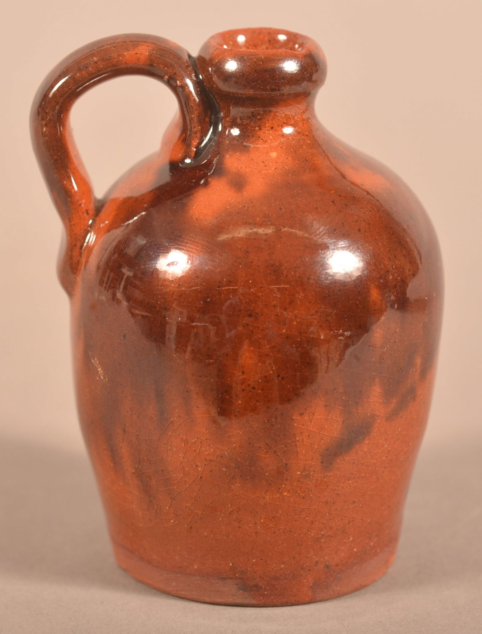 Pennsylvania 19th Century Miniature Redware Jug.: Pennsylvania 19th Century Miniature Redware Jug. Slightly bulbous form with loop handle and pleasing mottled glaze. Provenance: The late Eugene and Vera Charles, Lancaster, PA. 3-1/4"h.
