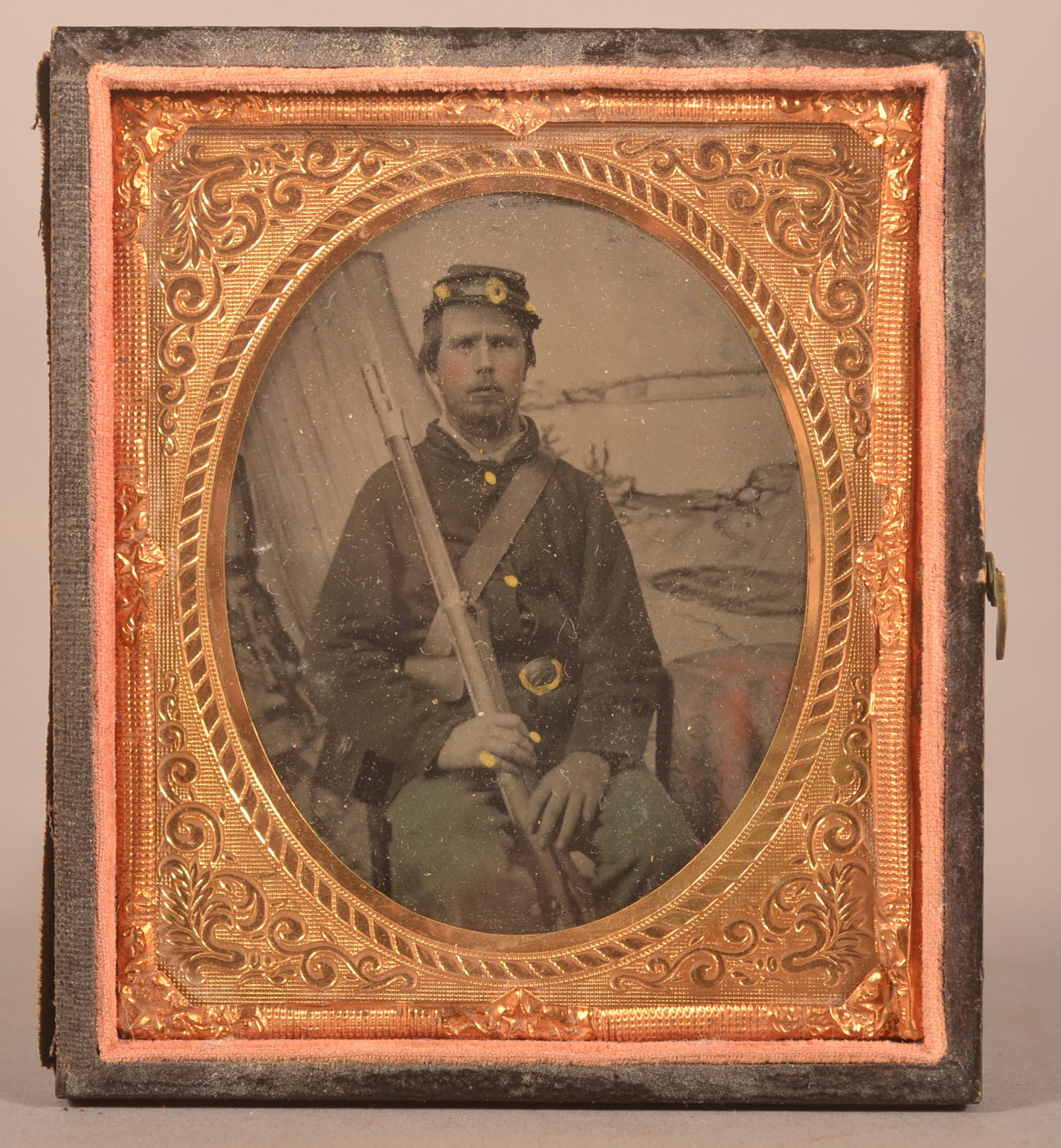 1/6th Cased Tintype of Armed Union Soldier: Clear image of a seated soldier in full uniform with contract musket, separated case cover with expected finish wear to the case.