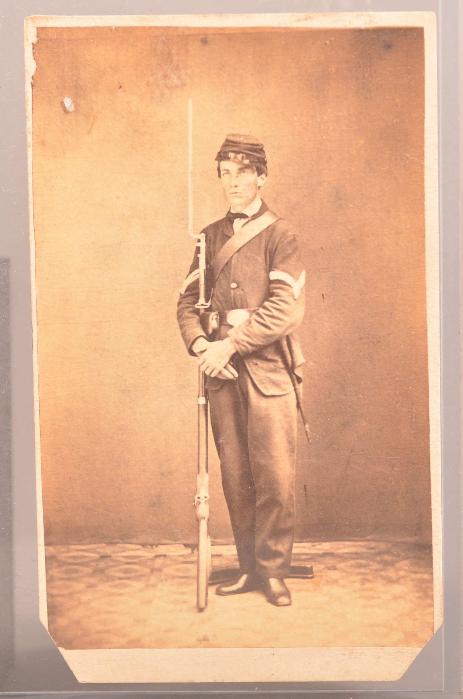 Unidentified CDV of Full Dressed Union Soldier: Standing studio image of union soldier in full uniform holding a contract musket, clear image with cut lower corners, normal wear and signs of age, backmarked for a Philadelphia photographer.