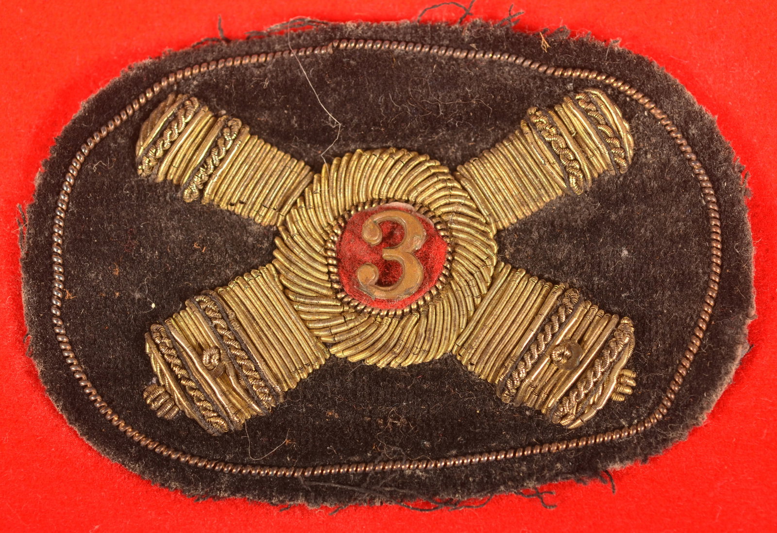 Artillery Officer Hat Badge: Cross cannon embroidered design, black cloth background with brass bullion, As-found removed condition with expected signs of age and wear, overall fair condition.