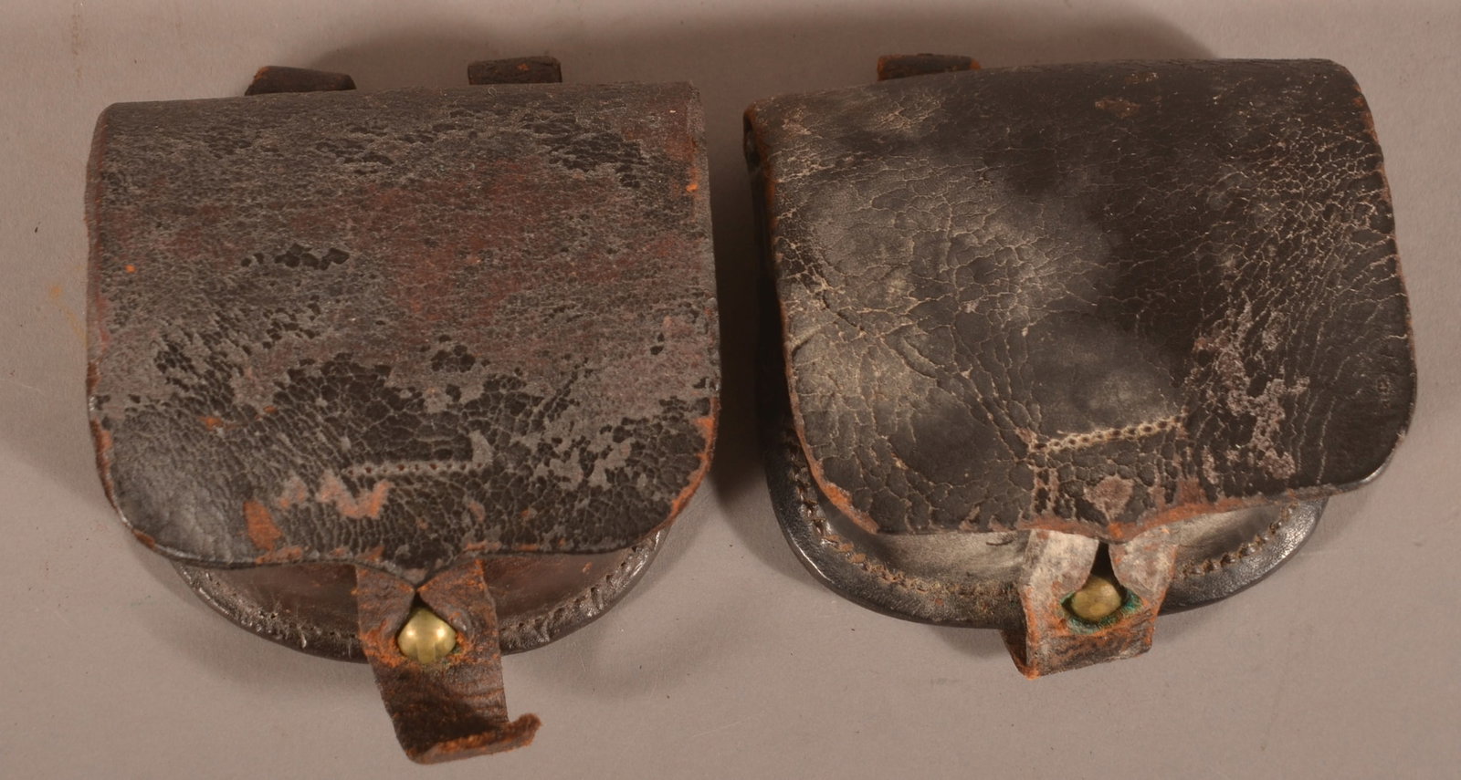 2 Unmarked Percussion Cap Boxes: Intact stitching and belt loops with one loop showing partial separation, one box shows remains of interior wool, excessive age cracks and crazing, dry, aged leather patina, signs of mildew, overall f